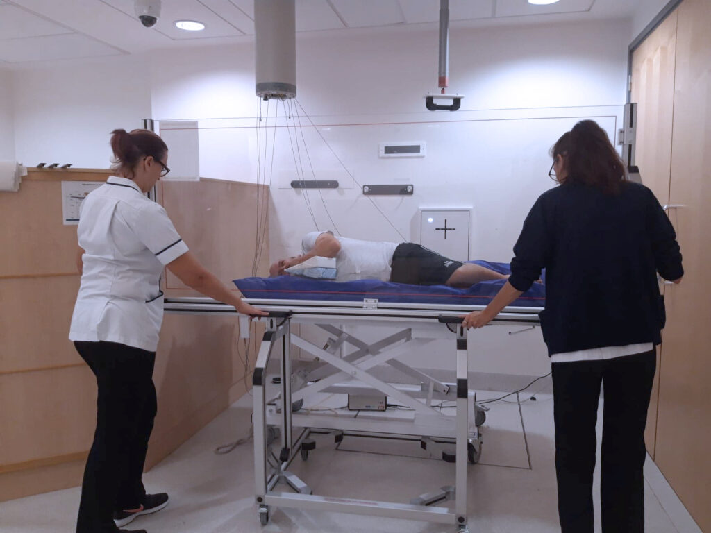 An image showing a patient lying down on a perspex screen on the treatment machine.