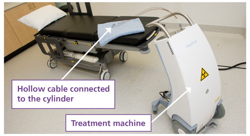 The image shows the treatment machine which holds the radioactive pellet. It also shows the cables down which the pellet will travel to deliver the radiation.