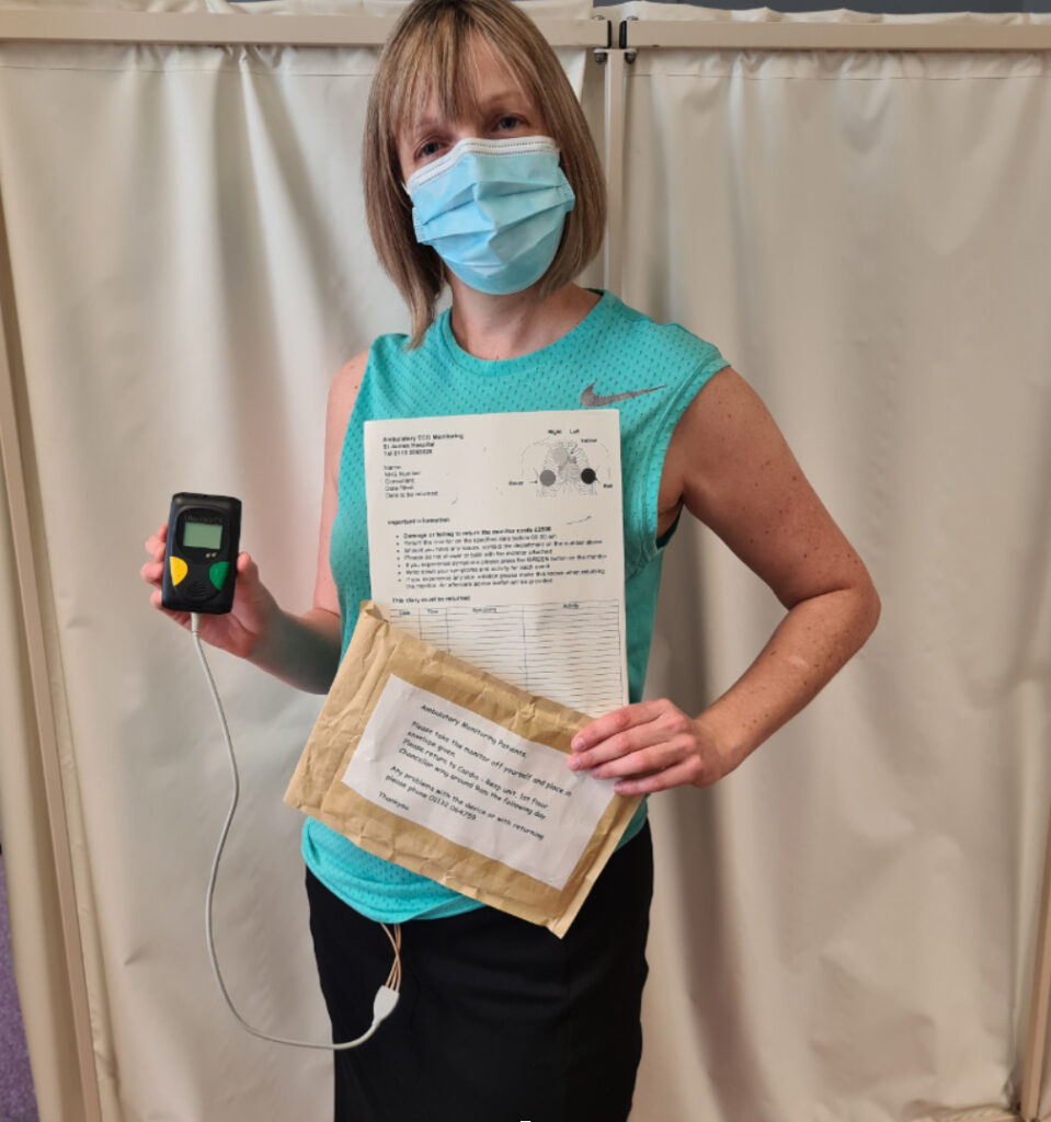 Photograph of a person wearing a ambulatory ECG monitor and holding instructions