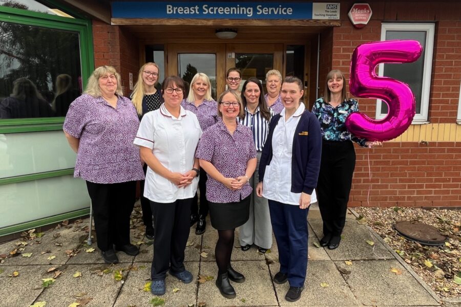 the Breast Screening team at Seacroft Hospital stands outside the building with a large number 5